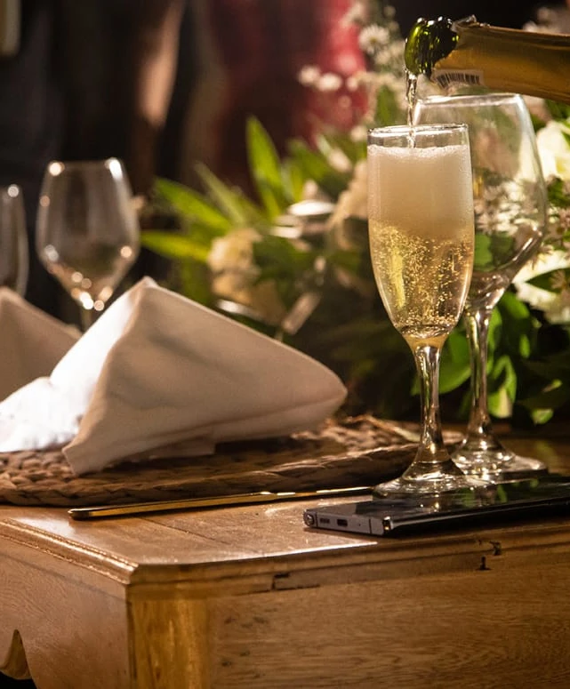 Copa de espumante sirviéndose en una mesa de cena romántica decorada con flores